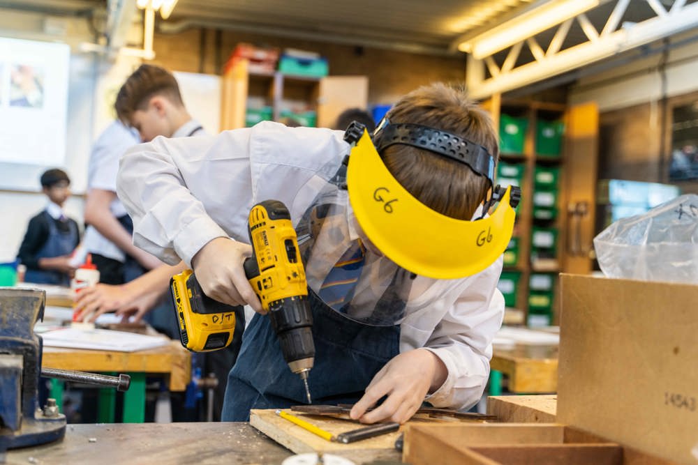 DT student wearing protective visor and using a drill